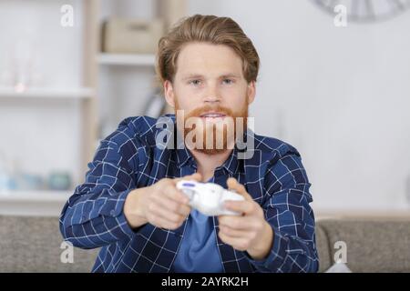 Ein aufmerksamer, schnell gewitterter Mann hält die Gaming-Ausrüstung Stockfoto