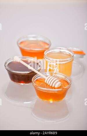 Vier Arten von kunsthandwerklichem Honig zusammen mit einem Honigwürger aus Holz Stockfoto