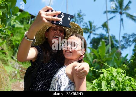 Zwei niedliche Teenager-Schwestern, die Selfies zusammen nehmen und dabei viel Spaß haben, sich vor der Kamera zu posieren Stockfoto