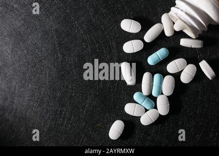Hochwinkeliger Blick auf das Auslaufen der weißen Tablette aus dem Behälter Stockfoto