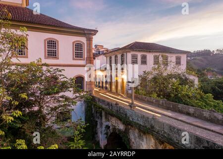 Schöne Landschaft mit Gebäuden im Kolonialstil und alter Brücke bei trübem Sonnenuntergang in Ouro Preto, Brasilien. Ouro Preto wurde zum Weltkulturerbe ernannt Stockfoto