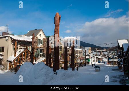 Street-Szene mit geschnitzten Holzmasten aus Ainu Kotan, einem kleinen Dorf aus Ainu in Akankohan, einer Straße, die von Souvenirläden gesäumt ist, auf die spezialisiert ist Stockfoto