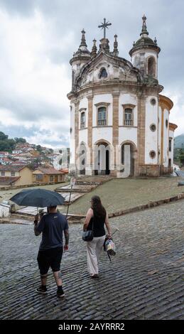 OURO PRETO, MINAS GERAIS, BRASILIEN - 22. DEZEMBER 2019: Eine Frau und ein Mann gehen in Ouro Preto - Brasilien entlang einer gepflasterten Straße. Stockfoto