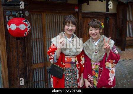 Junge Frauen kleideten sich in Kimonos in einer kleinen Straße im historischen Gion District von Kyoto, Japan. Stockfoto