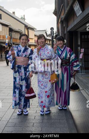 Junge Frauen kleideten sich in Kimonos in einer kleinen Straße im historischen Gion District von Kyoto, Japan. Stockfoto