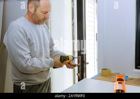 Nahaufnahme eines professionellen Bauschlosser installieren oder Reparieren eines neuen deadbolt Verschluss auf eine Haustür mit der Innenseite interne Teile des Schließmechanismus sichtbar. Stockfoto