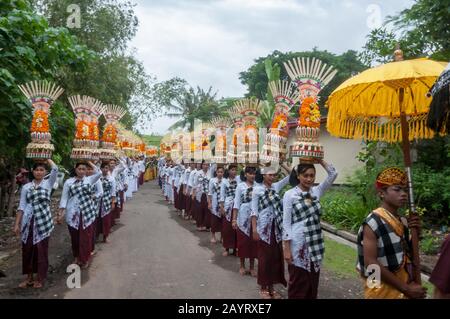 Bali, Indonesien - 26. Juli 2010: Gruppe von Frauen in traditionellen Kostümen und farbenfrohes Angebot auf dem Kopf gehen zum heiligen Pura Tanah Lot Tempel. Stockfoto