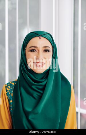 Porträt der jungen schönen muslimischen Frau in traditionellem Hijab mit Blick auf die Kamera Stockfoto