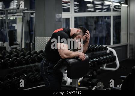 Problem und Ärger Kopfschmerzen müde Sport man hält seinen Kopf mit der Hand in der Fitness-Sporthalle Stockfoto
