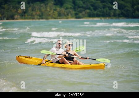 Fröhliches junges Paar verbringt ein Wochenende zusammen und paddelt Kajak auf dem See Stockfoto