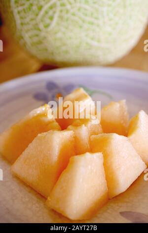 Platte mit Scheiben Muskmelon Cantaloupe mit Verschwommener Ganzer Frucht im Hintergrund Stockfoto