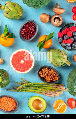 Veganes Essen, gesunde Ernährung Top Flat Lay Shot. Obst, Gemüse, Hülsenfrüchte, Pilze, Nüsse, von oben auf blauem Grund geschossen Stockfoto