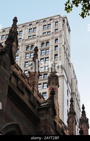 Blick auf die Spitze eines monumentalen neogotischen Wolkenkratzers mit zwei Rektoren an den gotischen Enden der Trinity Church NYC vorbei Stockfoto