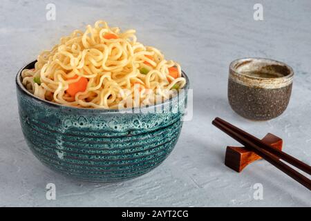 Nudelschüssel mit Karotten und Hengsten, mit Essstäbchen und Sake Stockfoto