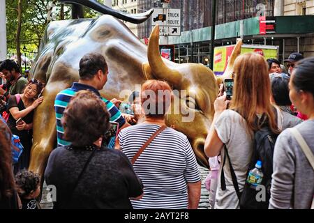 Das Bulls Eye des berühmten Charging Bull der Wall Street, umgeben von vielen Menschen, die an einem sonnigen Nachmittag in New York fotografieren und Selfies machen Stockfoto