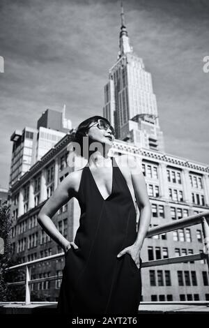 Lifestyle und Mode - Modische asianerin auf der Terrasse mit Blick auf die Spitze des Empire State Building in Midtown Manhattan, New York Stockfoto