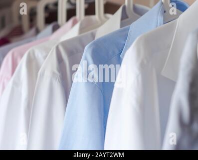 Mehrfarbige gebügelte Herrenshirts hängen an einem Bügel Stockfoto