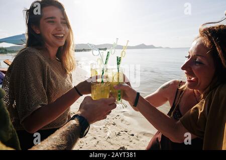 Eine Gruppe glücklicher Freunde, die köstliche Zitrucocktails trinken, wenn sie Zeit am Strand verbringen Stockfoto