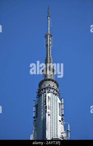Oben auf dem Mast, oben auf dem Empire State Building ein Blick aus nächster Nähe auf den Art déco-Wolkenkratzer in Midtown Manhattan, New York, mit langer Linse Stockfoto