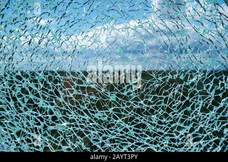 Risse Verbundglas Oberfläche gegen den blauen Himmel mit weißen Wolken unscharf im Hintergrund Stockfoto