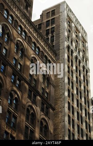 Mit Blick auf zwei sich verschließende Fassaden, neoklassizistische und Art déco-Details von New York City Wolkenkratzern aus dem Goldenen Zeitalter der Wolkenkratzer-Architektur Stockfoto