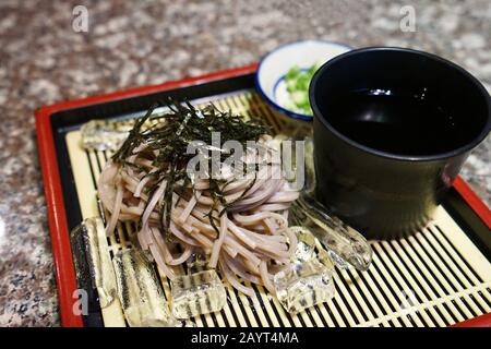 Schließen Sie Zaru Soba, japanische Nudeln mit Kaltschnulzen-Schnallen, die mit eintauchender Sojasoße serviert werden Stockfoto