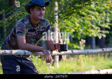 Man Kaffee trinken auf umzäunten Ranch in Morgen Stockfoto