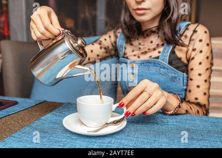 Eine Frau gießt Tee aus einem Wasserkocher in einem Restaurant Stockfoto