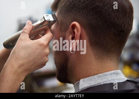 Schöne kaukasische Frau Friseursalon Frisur für Kunden. Nahaufnahme Portrait weiblicher barber mit Frisierwerkzeugen Trimmer bei der Arbeit. Haarschnitt Stockfoto