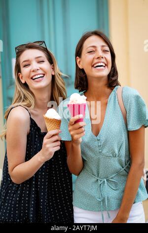 Zwei junge Freundinnen haben Spaß und essen Eis im Freien
