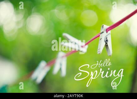 Weiße Kunststoff-Wäscheklappen hängen an rotem Seil mit schönem bokeh grünen Hintergrund. Stockfoto