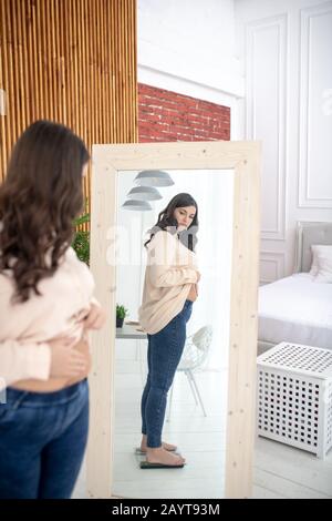 Junge Frau in einer beigefarbenen Bluse, die auf einer Waage steht Stockfoto