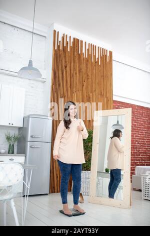 Junge Frau in einer beigefarbenen Bluse, die auf einem Gewand steht und frustriert ist Stockfoto