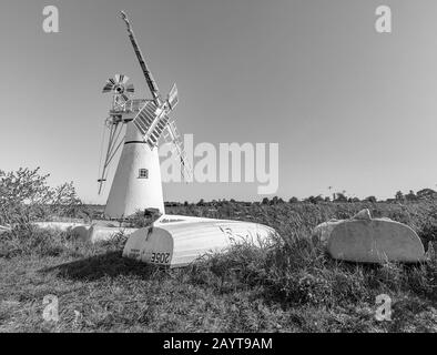 Tagesboote kopfüber am Flussufer mit Thurne Mill im Hintergrund Stockfoto