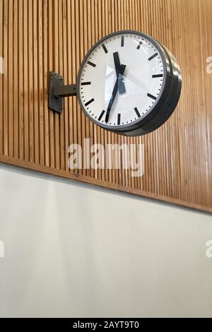 Dunkle Uhr im Flur, die an der Holzwand hängt Stockfoto