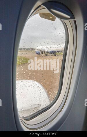 Fenster mit Regentropfen in einem kommerziellen Flugzeug öffnen. Innenraum der Kabine. Stockfoto