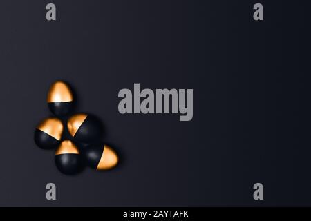 Sechs schwarze und goldene Ostereier auf schwarzem Grund. Flaches Layout, Draufsicht, Kopierbereich. Stockfoto