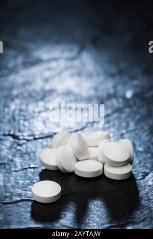 Nahaufnahme von gestapelten Rundtabletten auf einer Schieferplatte im Rücklicht. Stockfoto