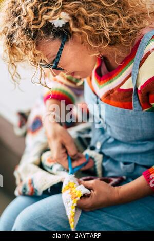 Passen Sie die Aktivität zu Hause an die kunstvolle, hippy Frau, die mit Stoff arbeitet - handgefertigte Kunsthandwerksbekleidung aus - Menschen, die bei hom arbeiten Stockfoto