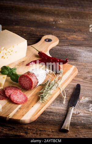 Trockener Salami oder Wurst mit Käse und Brot. Basilikum, Rosmarin und Chili. Stockfoto