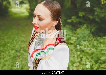 Eine Frau in traditioneller, gestickter Turkostkleidung führt im Park einen Nationaltanz aus Stockfoto