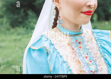 Eine Frau in traditioneller, gestickter Turkostkleidung führt im Park einen Nationaltanz aus Stockfoto