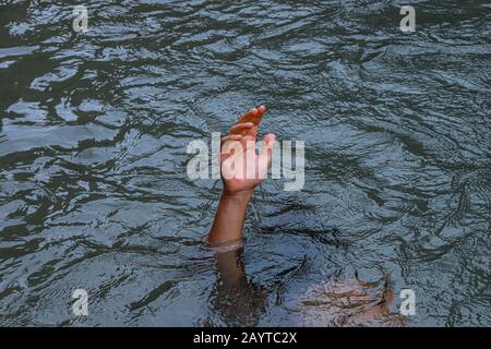 Eine Hand, die aus dem Wasser reicht, um das Konzept des Ertrinkens, der psychischen Krise, der Depression und des Kampfes zu zeigen Stockfoto