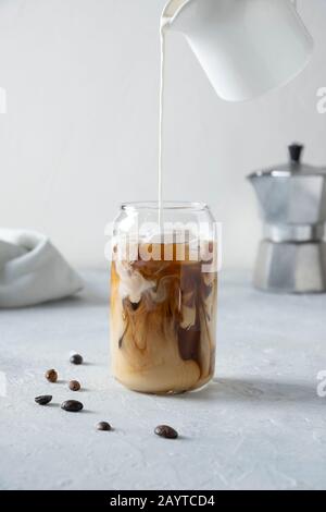 Eiskaffee aus Glas mit Milch auf Grau. Nahaufnahme. Vertikales Format. Stockfoto