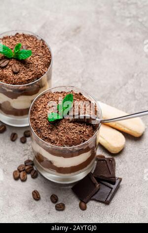 Classic Tiramisu Dessert im Glas Schale, savoiardi Cookies und Stücke Schokolade auf konkreten Hintergrund Stockfoto