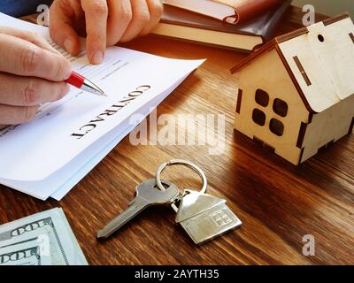 Käufer unterzeichnet Vertrag für den Kauf von Immobilien und kleines Haus in der Nähe. Stockfoto