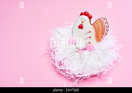 Stilvoller rosafarbener Hintergrund mit verschiedenen Plätzchen in Form von Eiern und Huhn, die mit bunter Glasur bemalt sind. Osterrahmen, Kopierbereich, Draufsicht. Stockfoto