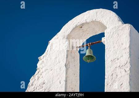 Traditioneller weißer stuckierter Kirchturm der griechischen Inselkirche, der gegen den lebhaften blauen Himmel in Mykonos, Griechenland steht Stockfoto