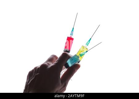 Drei Spritzen mit leuchtend roten, grünen, blauen Adn-Flüssigkeiten werden in einer Hand isoliert auf weißem Hintergrund gehalten Stockfoto