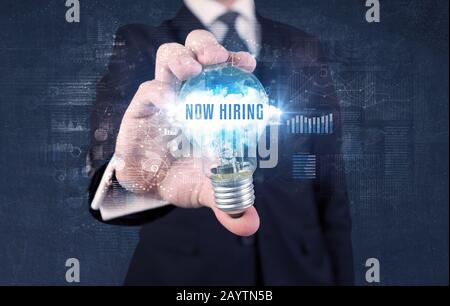 Geschäftsmann, der eine Glühbirne mit JETZT EINSTELLENDER Aufschrift hält, neues Geschäftskonzept Stockfoto
